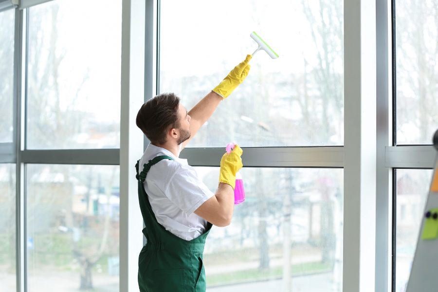 Male Janitor Cleaning Window in Office