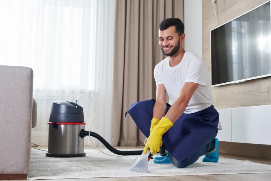 Man Cleaning Carpet In The Living Room Using Vacuum Cleaner At Home. Cleaning service concept